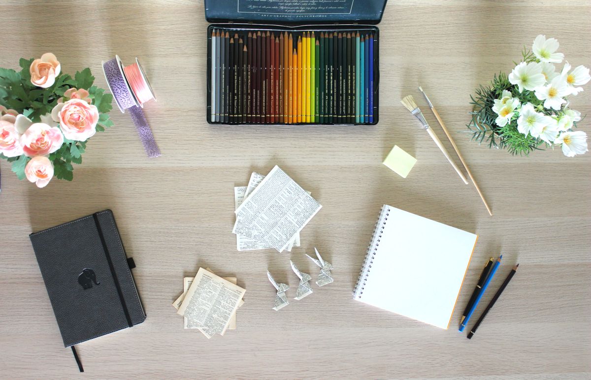 Paper, colored pencils, and creative materials arranged on a wooden desk